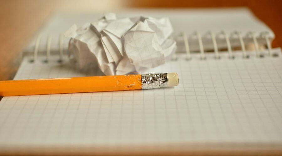 Un crayon et d'une feuille roulée en boule posés sur un cahier à spirales